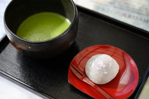 Ceremonial grade matcha in a bowl with a red plate.